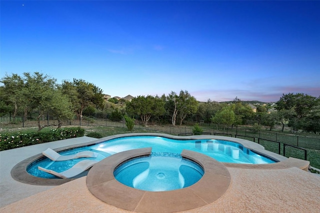 view of pool with a fenced backyard and a pool with connected hot tub