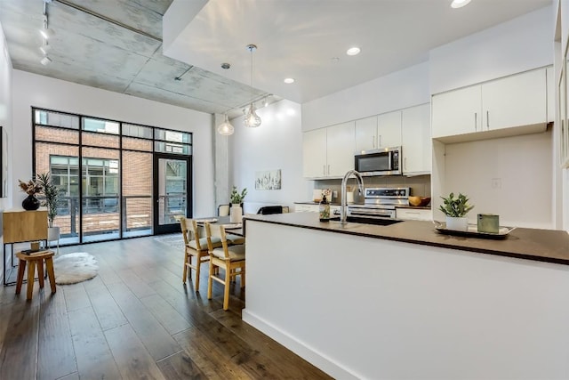 kitchen with stainless steel appliances, rail lighting, dark wood-type flooring, white cabinets, and recessed lighting