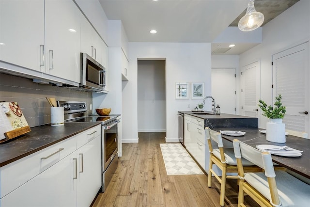 1501 E 4th St Unit 206, Austin, TX 78702 - kitchen featuring appliances with stainless steel finishes, light wood-style floors, white cabinets, backsplash, and recessed lighting