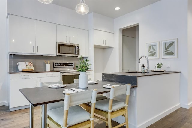 1501 E 4th St Unit 206, Austin, TX 78702 - kitchen with stainless steel appliances, dark countertops, white cabinetry, backsplash, and recessed lighting