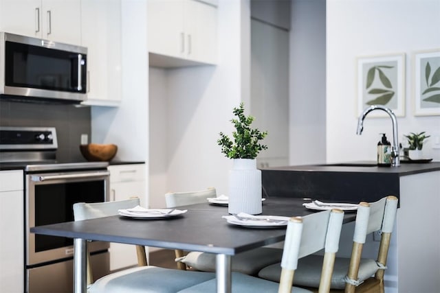 1501 E 4th St Unit 206, Austin, TX 78702 - kitchen featuring appliances with stainless steel finishes, dark countertops, and white cabinetry