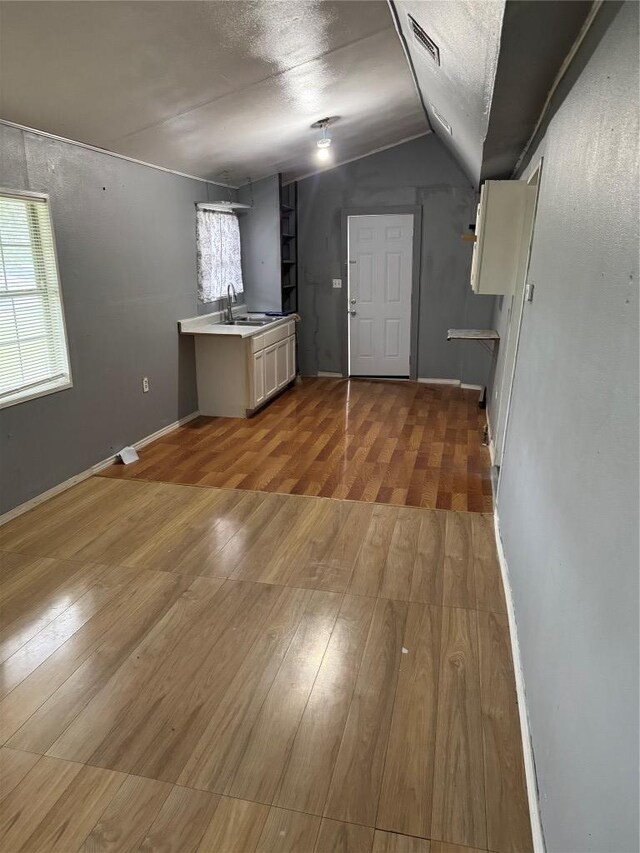 below grade area with wood finished floors, visible vents, baseboards, and a sink