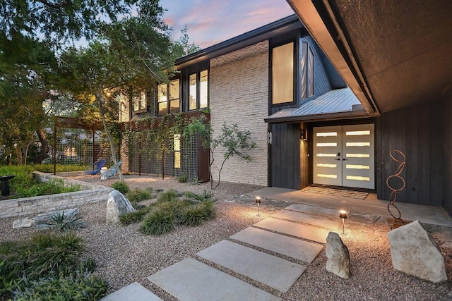 1213 Falcon Ledge Dr, Austin, TX 78746 - exterior entry at dusk featuring a metal roof