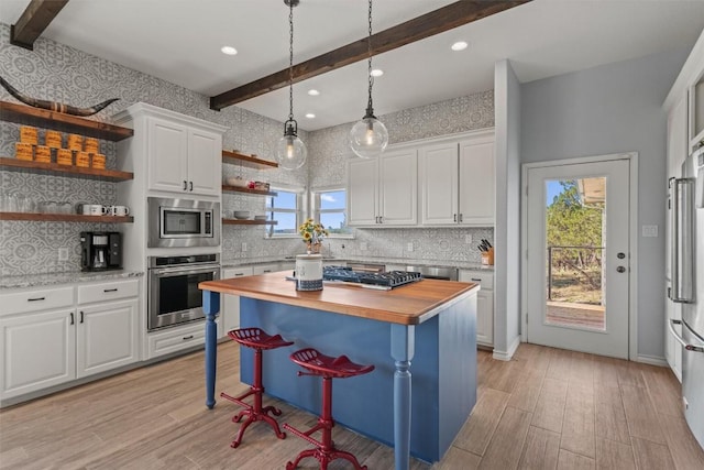 kitchen with white cabinets, beamed ceiling, open shelves, wooden counters, and appliances with stainless steel finishes