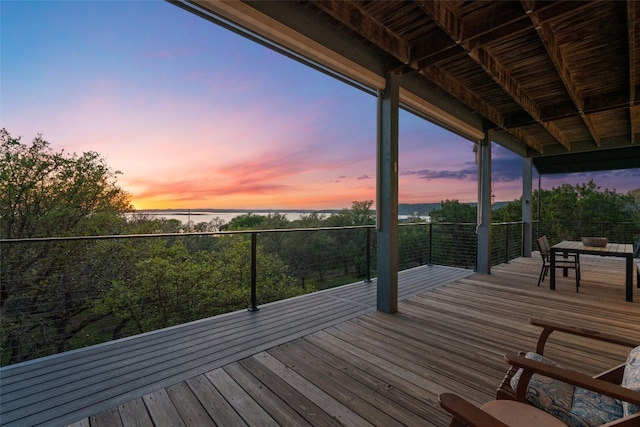 deck at dusk featuring a water view