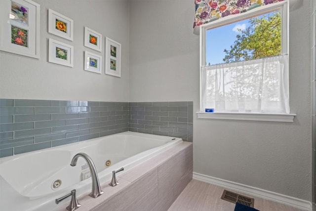 bathroom featuring baseboards, visible vents, and a whirlpool tub