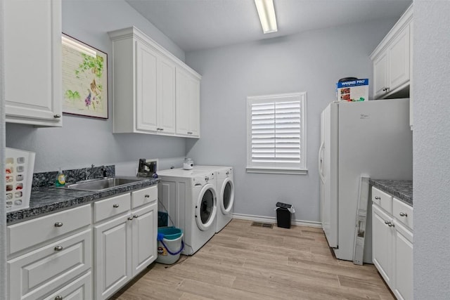washroom featuring a sink, cabinet space, light wood finished floors, washing machine and dryer, and visible vents