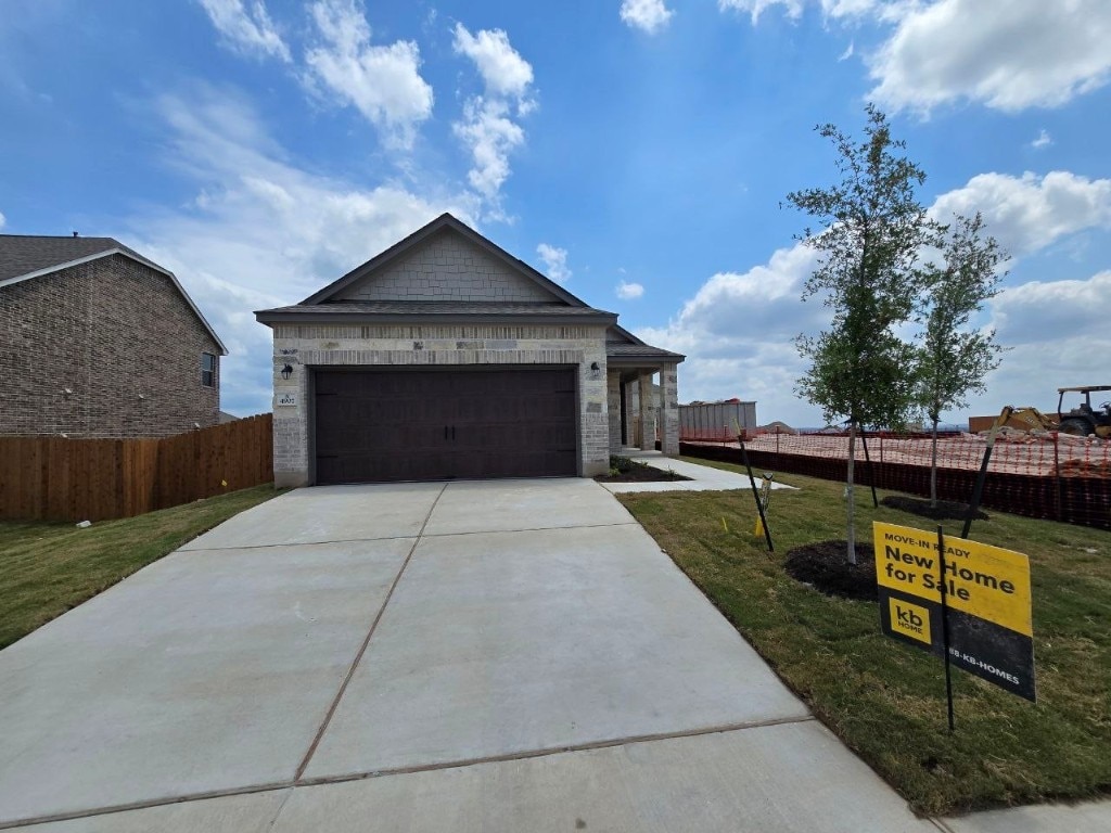 ranch-style house with fence, concrete driveway, a front lawn, and a garage
