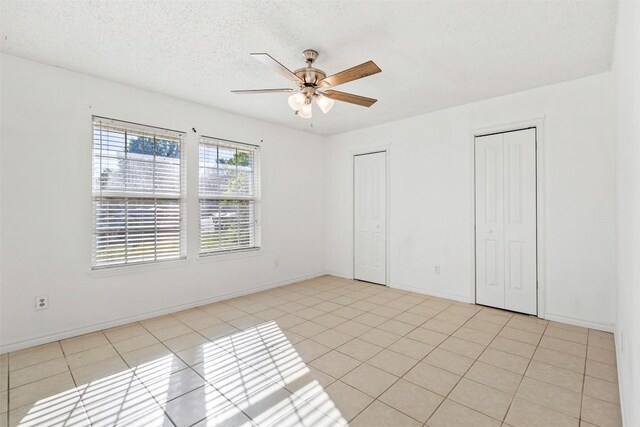 2210 Lasso Dr, Round Rock, TX 78681 - unfurnished bedroom featuring two closets, ceiling fan, baseboards, and light tile patterned floors