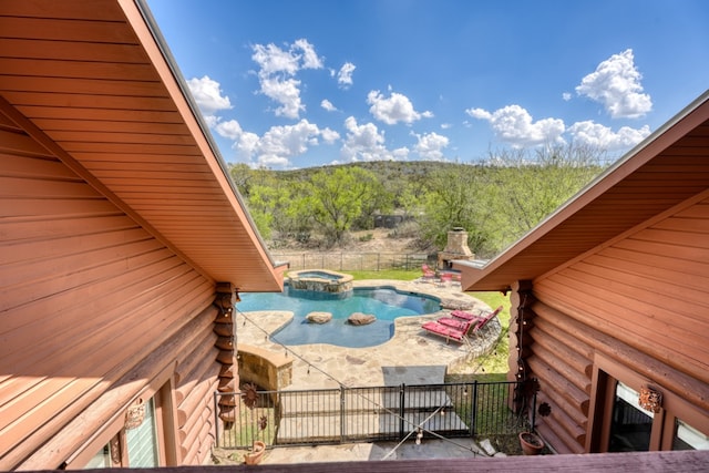 exterior space featuring log exterior, fence, a patio area, an in ground hot tub, and a forest view
