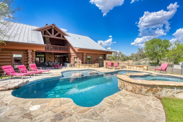 view of pool featuring a bar, a patio area, a pool with connected hot tub, and fence