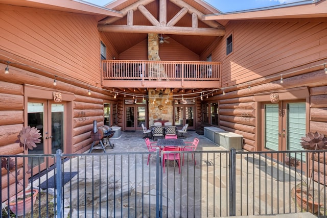 exterior space with a patio area, french doors, log exterior, and a balcony