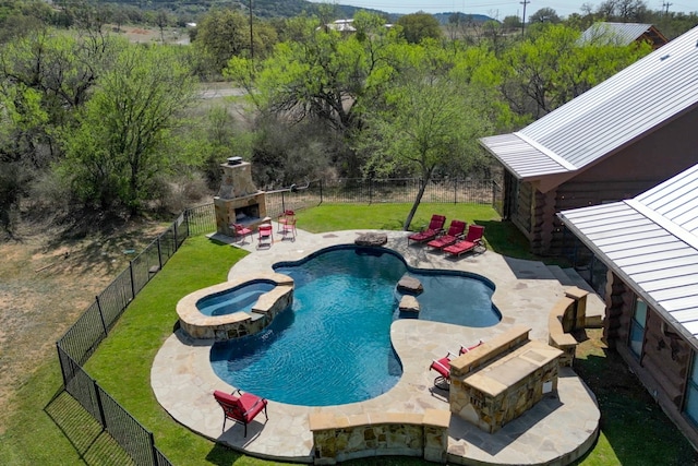 view of pool with an outdoor stone fireplace, a fenced backyard, a patio area, a lawn, and a pool with connected hot tub