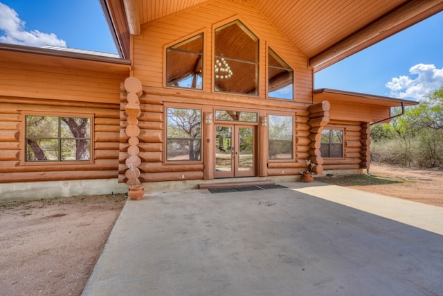 view of exterior entry with a patio area, french doors, and log siding