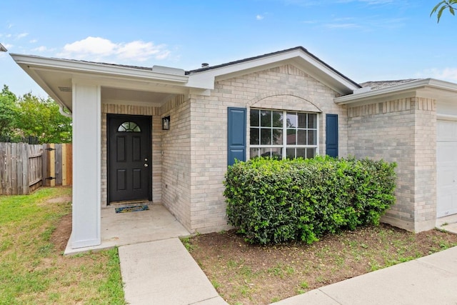 property entrance featuring fence, brick siding, and a garage