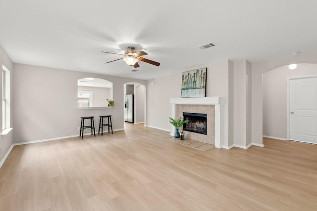 living room with arched walkways, visible vents, ceiling fan, and a fireplace