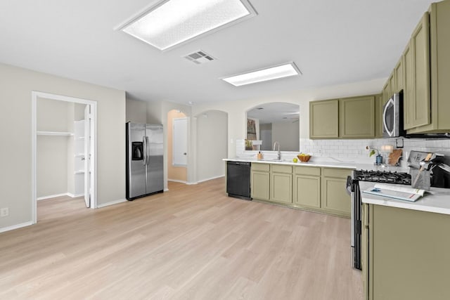 kitchen featuring stainless steel appliances, arched walkways, green cabinetry, visible vents, and light countertops