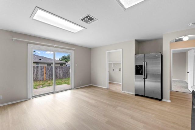 unfurnished living room featuring baseboards, light wood-style floors, and visible vents
