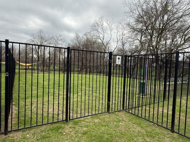 view of gate featuring a lawn and fence