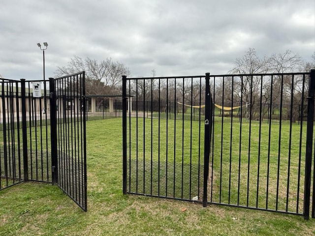 view of gate with a lawn and fence