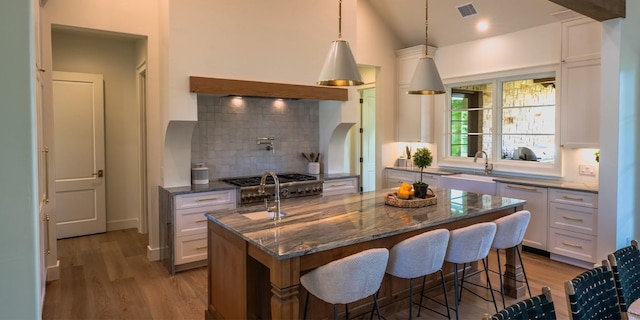kitchen featuring backsplash, wood finished floors, visible vents, and white cabinets