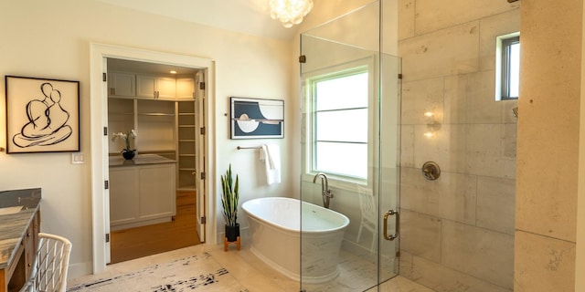 bathroom featuring a walk in closet, a freestanding tub, vanity, and a stall shower