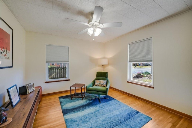 sitting room with baseboards, a ceiling fan, and wood finished floors