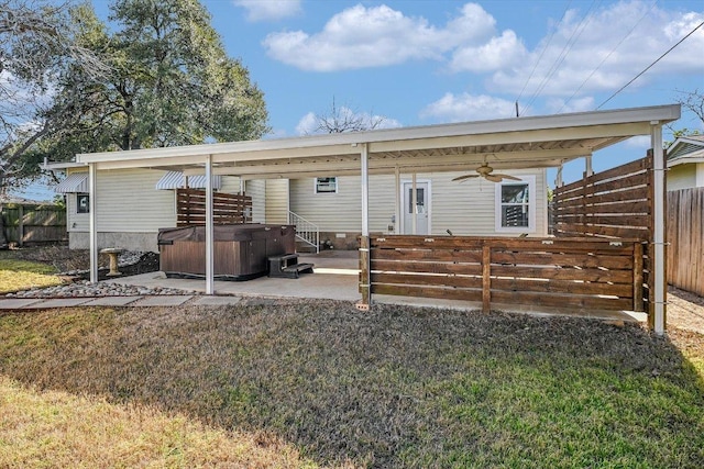 rear view of house with a ceiling fan, a fenced backyard, a yard, a patio, and a hot tub