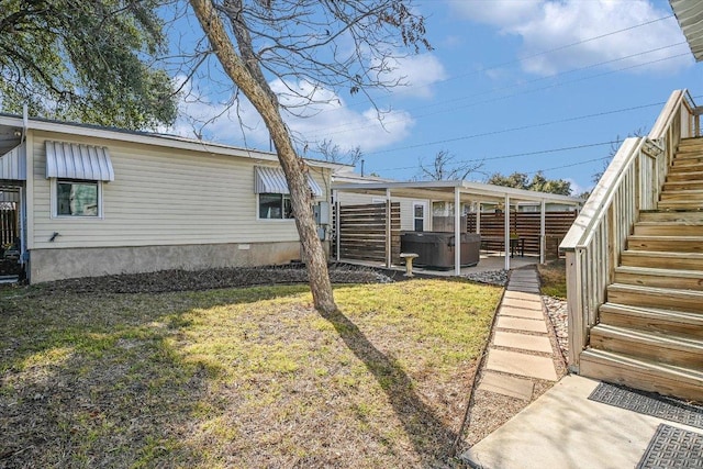 rear view of house featuring a lawn, fence, a hot tub, and stairs