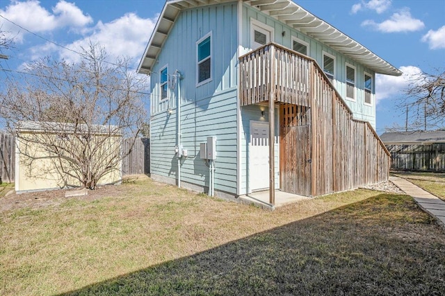 rear view of property with board and batten siding, a lawn, and fence