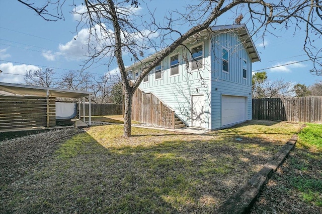 view of side of property featuring board and batten siding, stairs, a yard, and a garage