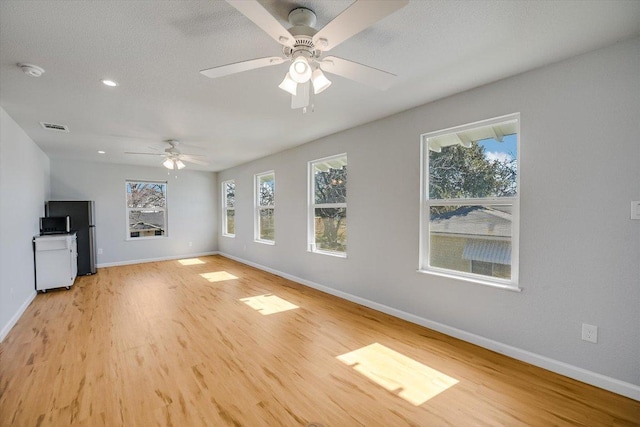 unfurnished living room with ceiling fan, baseboards, light wood-style floors, and visible vents