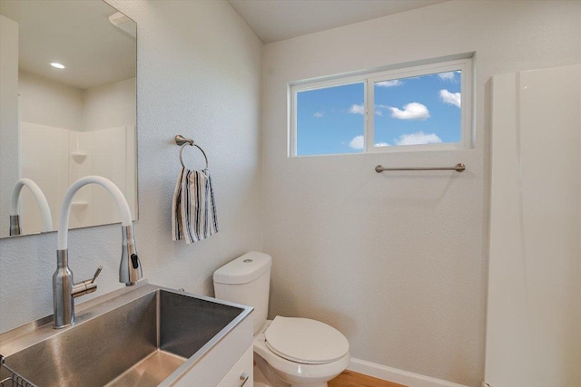 full bath featuring toilet, vanity, a shower, and baseboards