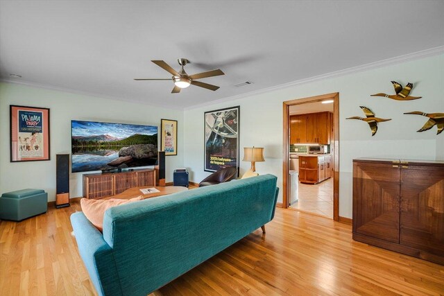 living area featuring baseboards, visible vents, a ceiling fan, wood finished floors, and crown molding