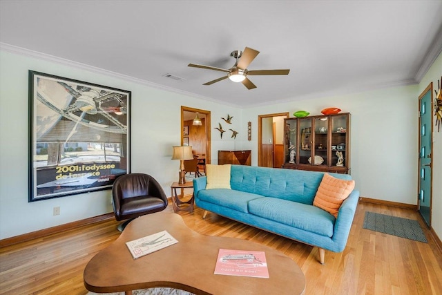 living room with wood finished floors, ornamental molding, baseboards, and ceiling fan