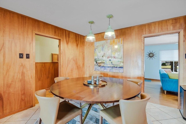 dining space featuring wooden walls and light tile patterned floors