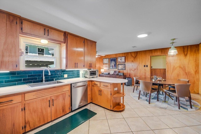 kitchen featuring a sink, dishwasher, light countertops, backsplash, and a peninsula