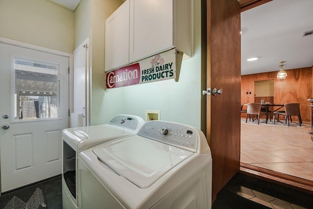 laundry room with washing machine and clothes dryer, dark tile patterned flooring, wooden walls, laundry area, and visible vents