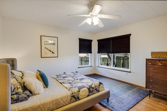 bedroom featuring baseboards, a ceiling fan, and wood finished floors