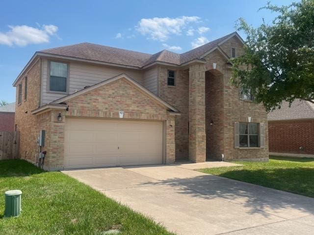 traditional-style home with fence, a front lawn, concrete driveway, brick siding, and a garage