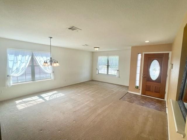 carpeted foyer featuring a chandelier and visible vents
