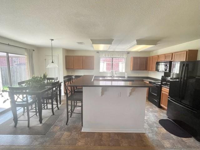 kitchen featuring a kitchen breakfast bar, a sink, a textured ceiling, black appliances, and a kitchen island