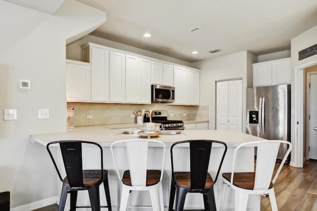 184 Martha Ln, Kyle, TX 78640 - kitchen with appliances with stainless steel finishes, a peninsula, decorative backsplash, light countertops, and recessed lighting