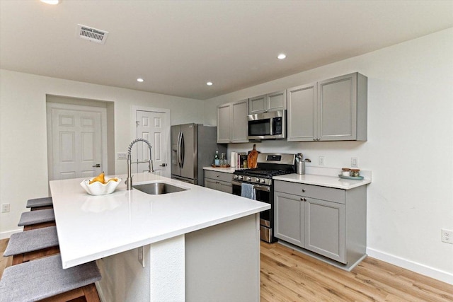 6300 Merriwood Dr, Austin, TX 78745 - kitchen with stainless steel appliances, gray cabinets, a kitchen breakfast bar, light wood-style floors, and recessed lighting