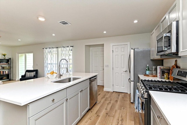 6300 Merriwood Dr, Austin, TX 78745 - kitchen with stainless steel appliances, a kitchen island with sink, light wood-style floors, light countertops, and recessed lighting