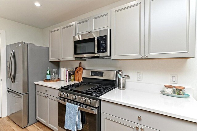 6300 Merriwood Dr, Austin, TX 78745 - kitchen featuring stainless steel appliances, gray cabinetry, light countertops, light wood finished floors, and recessed lighting