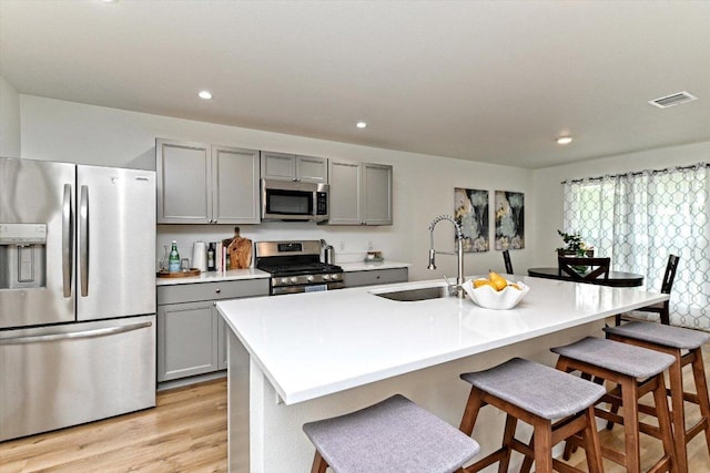 6300 Merriwood Dr, Austin, TX 78745 - kitchen with stainless steel appliances, gray cabinetry, light wood finished floors, a breakfast bar area, and recessed lighting