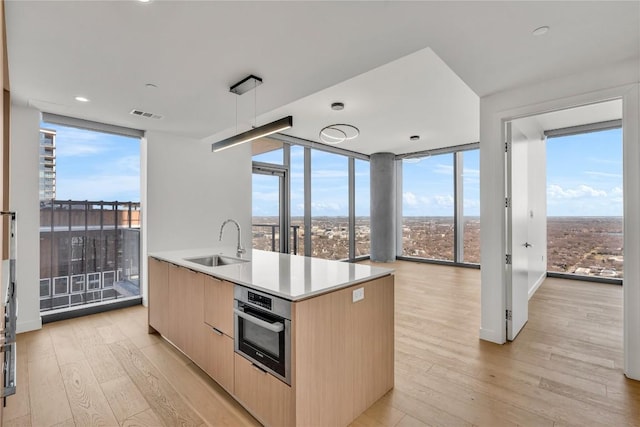 44 E Ave Unit 3107, Austin, TX 78701 - kitchen with a sink, light brown cabinets, expansive windows, modern cabinets, and stainless steel oven