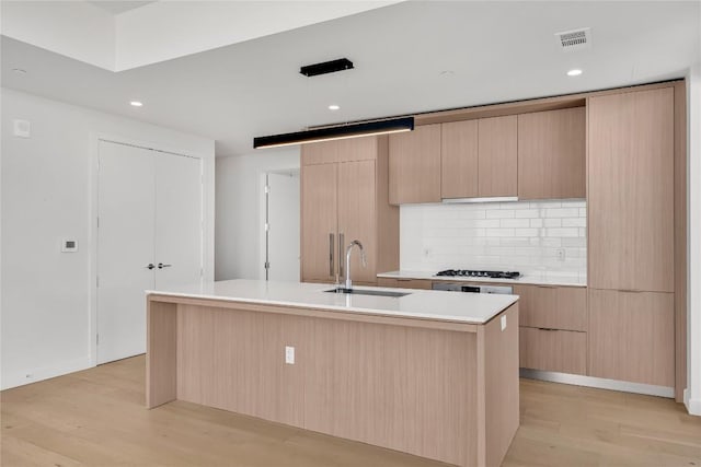 44 E Ave Unit 3107, Austin, TX 78701 - kitchen with tasteful backsplash, modern cabinets, light wood-style flooring, light brown cabinetry, and a sink