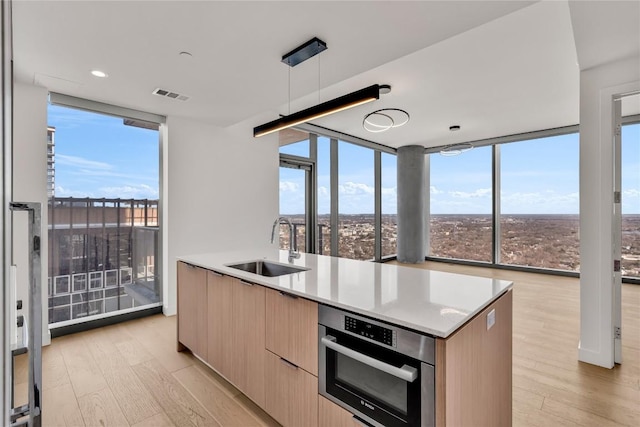 44 E Ave Unit 3107, Austin, TX 78701 - kitchen with expansive windows, oven, light brown cabinetry, a sink, and modern cabinets
